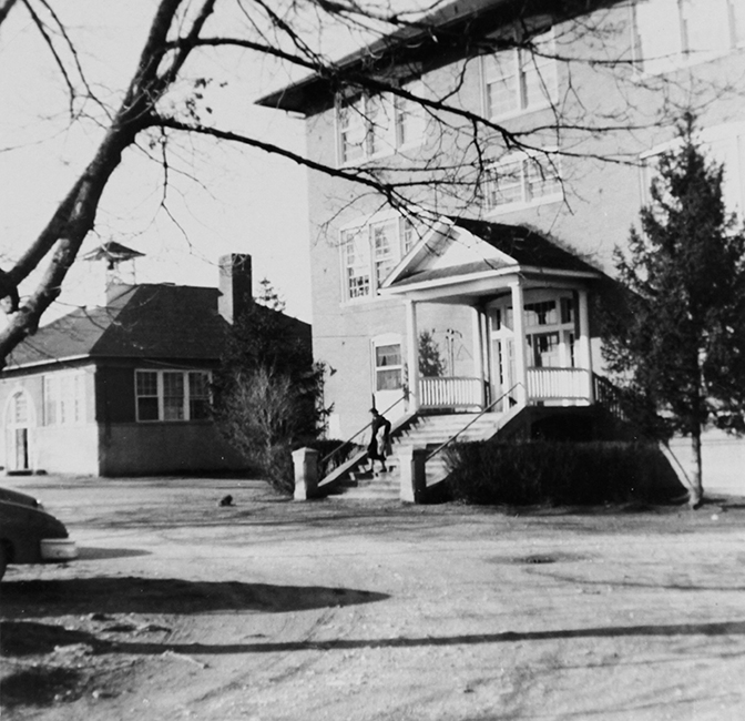 Black and white photograph from 1955 showing the two schools at Floris. One is a single-story building with a bell tower on the roof. The second building is much larger with three stories. 